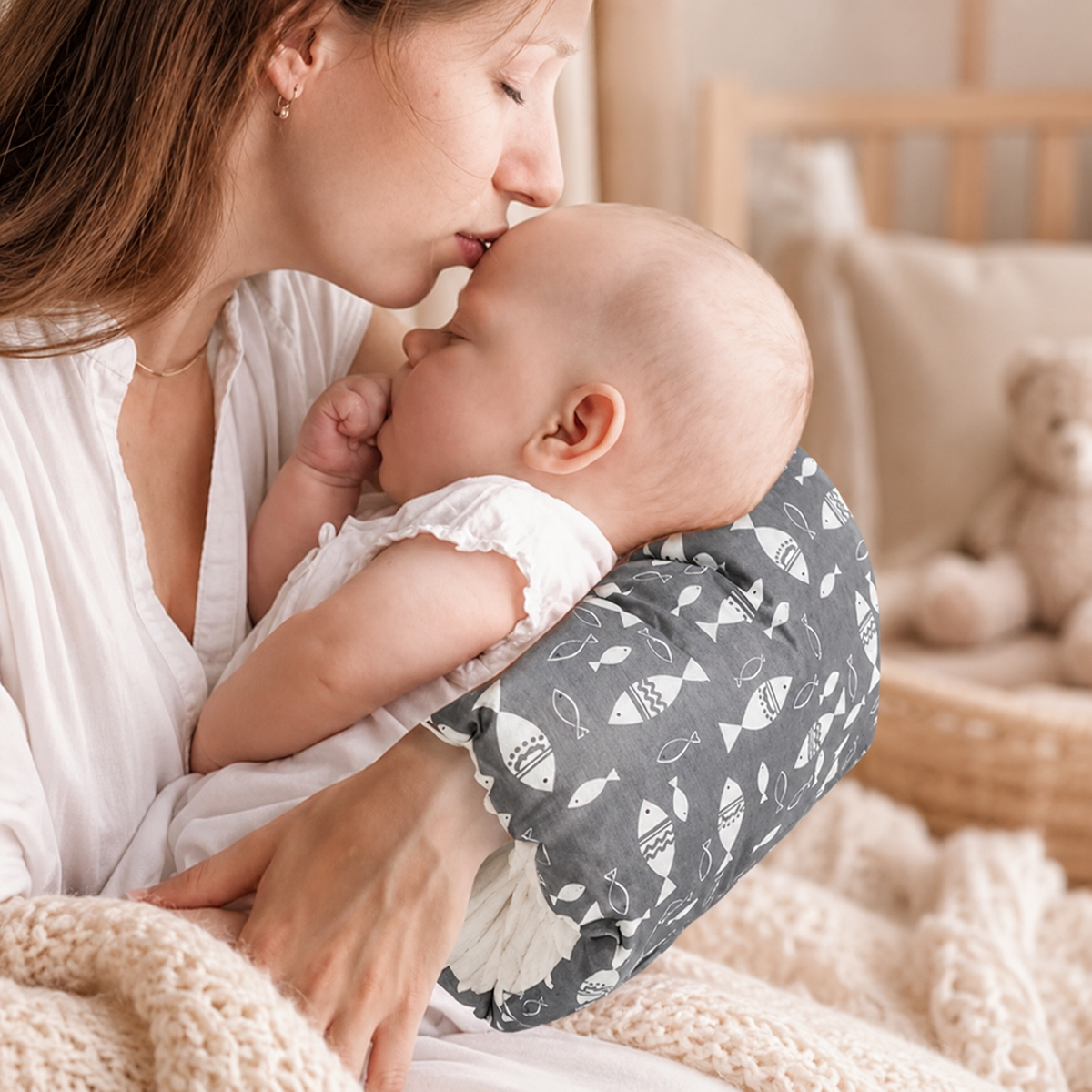 Maman embrassant son bébé, tête posée sur le coussin d'allaitement de bras Numa (motif poissons gris)