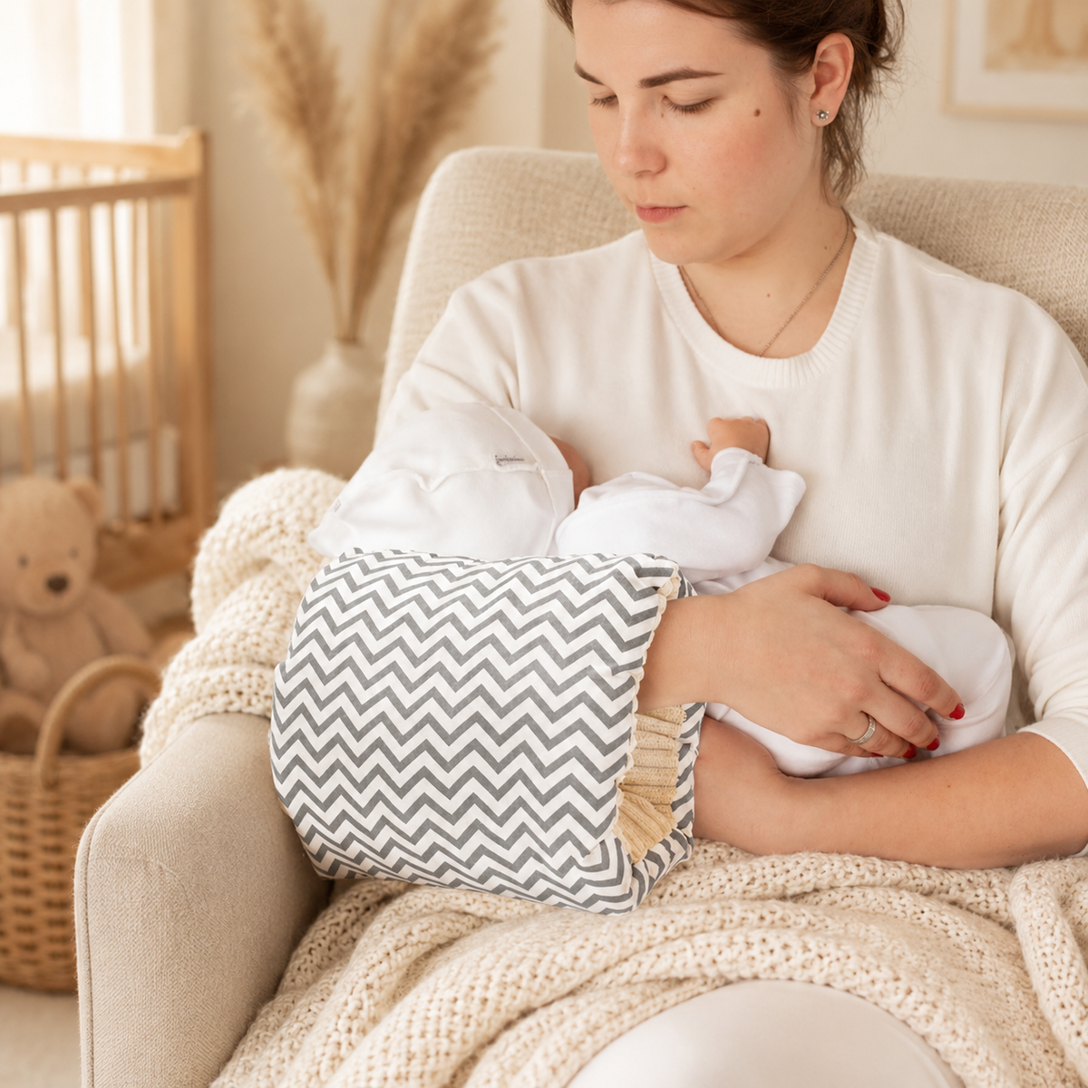 Coussin d'allaitement de bras Numa motif chevron gris porté au bras d'une maman